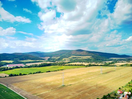 An aerial view of houses and large fields in a rural area under blue cloudy sky