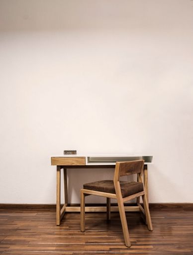 wooden desk with chair, plants in the room, natural sunlight coming in, pasta tile floor, white painted walls