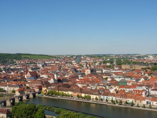 An aerial view of a river and dense red-roofed buildings under the clear blue sky, Bavaria, Germany