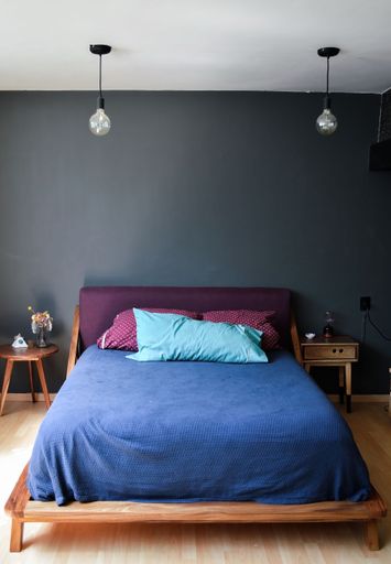 A vertical shot of a cozy bed in a bedroom with two lockers