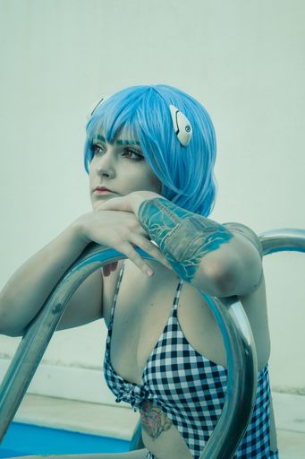 A shallow focus shot of a European female with blue hair covered in tattoos enjoying herself at the pool