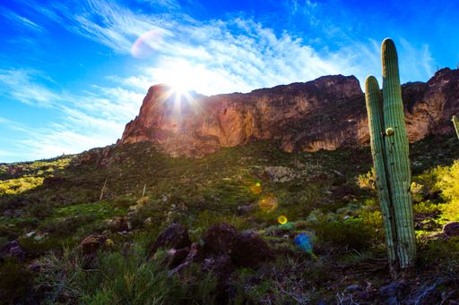 The beautiful scenery of the desert during the day with sunlight shining over high rocks and amazing cloudy blue sky