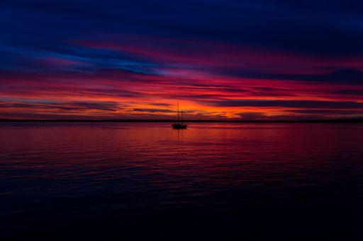 Beautiful shot of the red sunset at the seaside with a boat in the middle