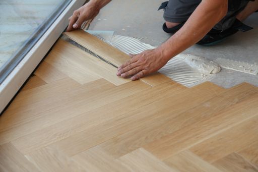 A closeup of a worker installing wooden laminate flooring