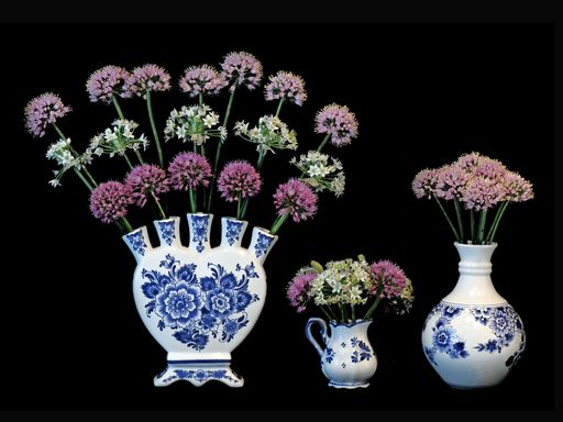 A closeup shot of allium flowers in floral vases against the black background