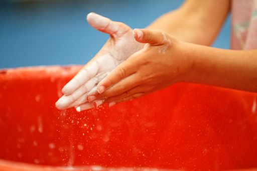 A closeup shot of a kid washing hands in a plastic pail