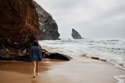 A female walking on the wet sand washed by the waters of the turbulent sea