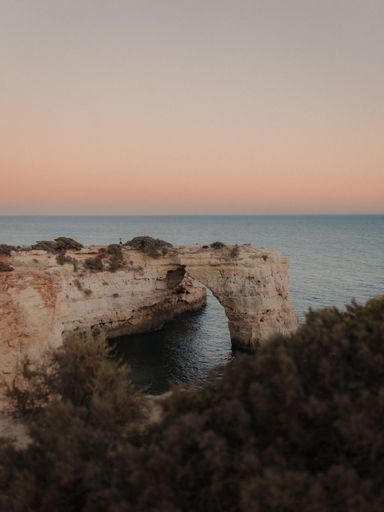A landscape scene of the Arco De Albandeira, Algarve, Portugal at sunset, vertical shot