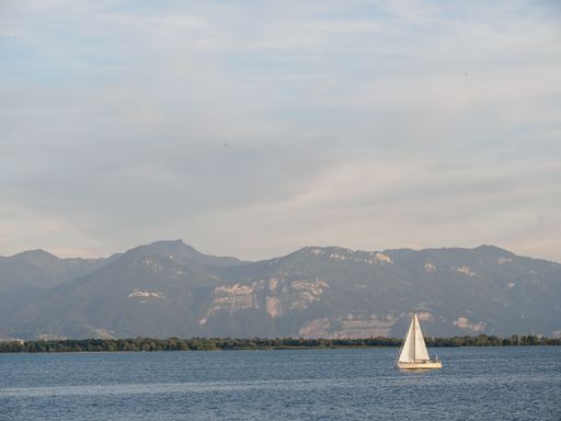 A sailing boat is gliding across Lake Constance against the background of mountains. Lindau, Germany.