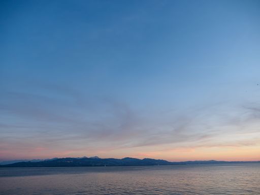 The tranquil waters of lake Constance (Bodensee) with Swiss Alps in the background on summer day on Lindau island, Germany