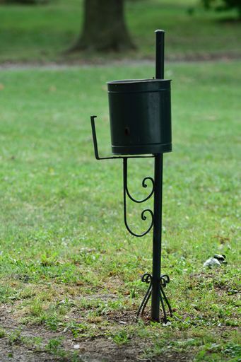 A vertical of a black public trash can outdoors.