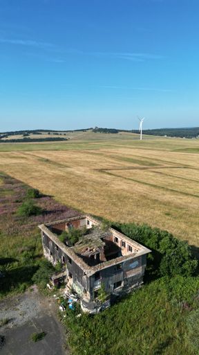 A vertical aerial shot of an abandoned house in the field