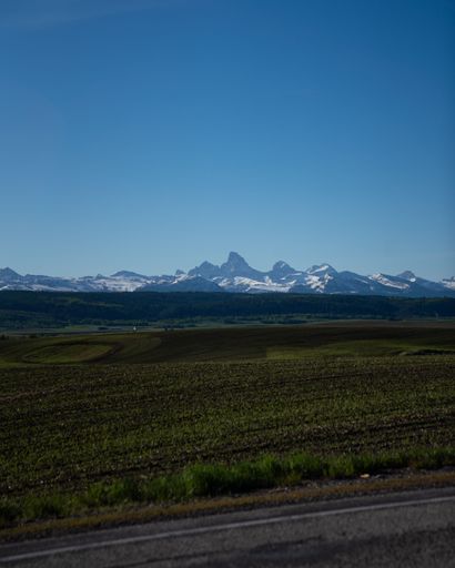 A vertical shot of road, empty grass plain and mountain range in the background