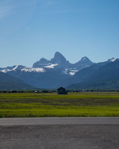 A vertical shot of road, empty grass plain and mountain range in the background