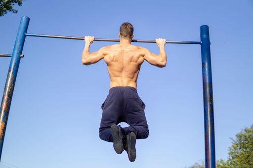 A muscular Caucasian man workout pull ups at outdoor