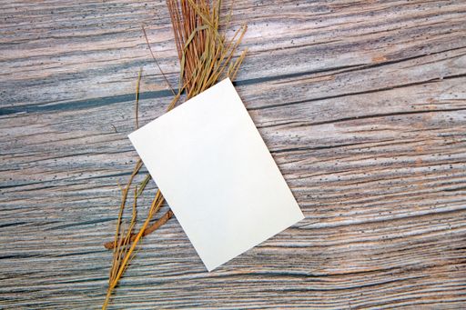 A top view of a blank sheet of paper with copy space and dried plants on a wooden surface
