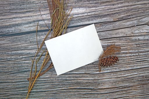 A top view of a blank sheet of paper with copy space and dried plants on a wooden surface