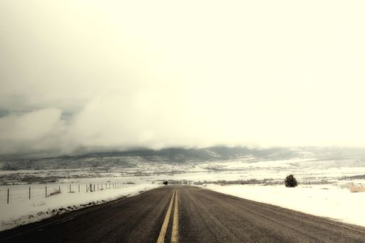 A beautiful shot of a highway in the center of a valley covered with snow under the white foggy sky