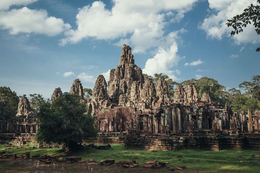 An aerial view of Angkor Wat temple surrounded by growing trees under blue bright sky