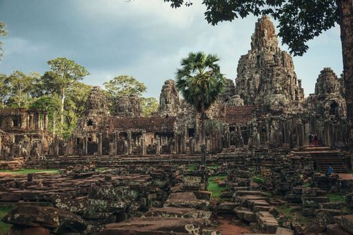 An aerial view of Angkor Wat temple surrounded by growing trees under blue bright sky