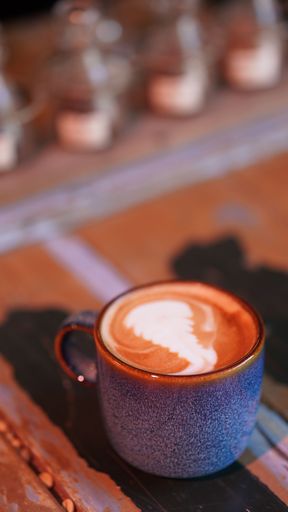 A closeup shot of a cappuccino coffee mug with latte art on top with blur background