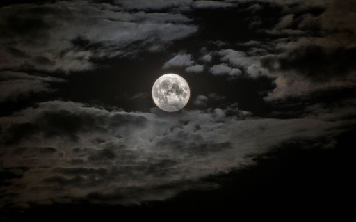 A beautiful view of full moon in a dark sky with clouds