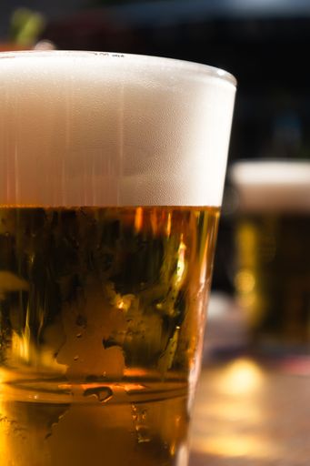 A vertical closeup of glass of beer with thick layer of white foam