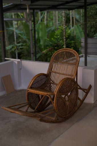 A vertical shot of a rocking chair in a backyard of a house