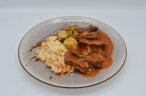 A closeup shot of pork with sauce with rice and potatoes