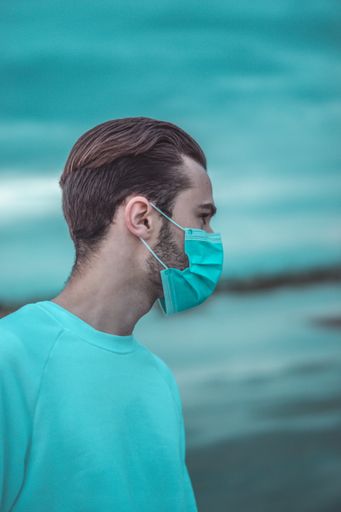 A closeup shot of a young male with a protective mask with blue sea in the background