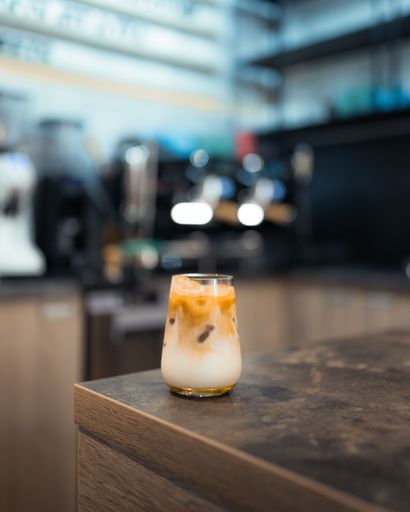 A vertical selective focus shot of an iced coffee glass on a wooden table