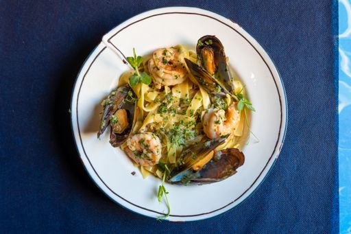 A top view of pasta with oysters and greens served on a plate