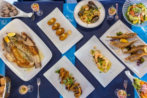 A top view of a dining table with different dishes with seafood, meat, and vegetables