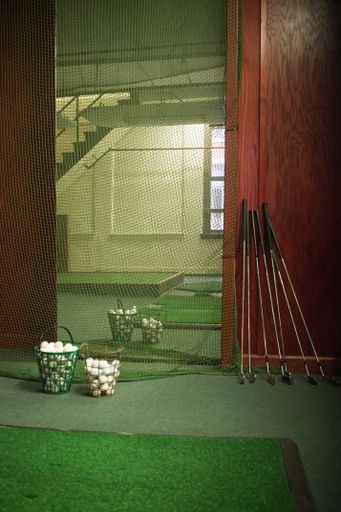 A vertical shot of a golf practice room with irons and golf balls