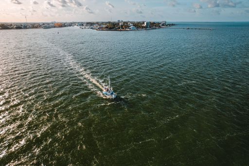 An aerial shot of fishermen on boats sailing in the ocean and leaving Belize City