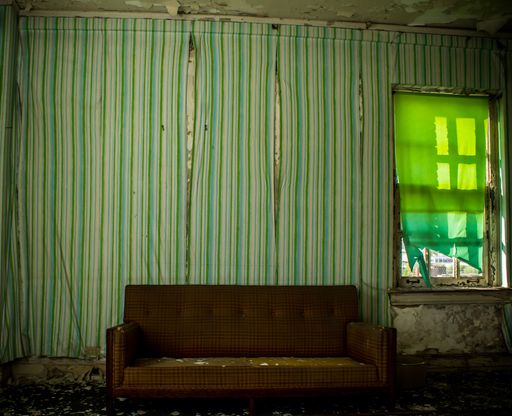 An interior view of an old, abandoned apartment with worn-out furniture covered in dirt