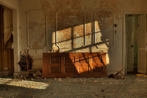 An interior view of an old, abandoned apartment with worn-out furniture covered in dirt