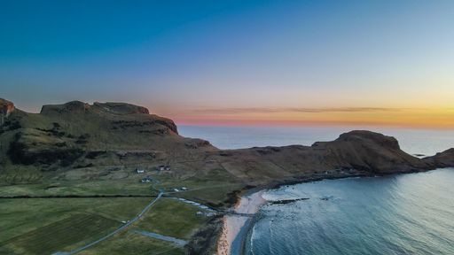 A beautiful view of a mountainous area next to a sea during a bright summer sunset