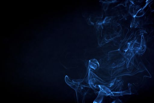 A closeup of smoke under the lights on a dark background - perfect for wallpapers