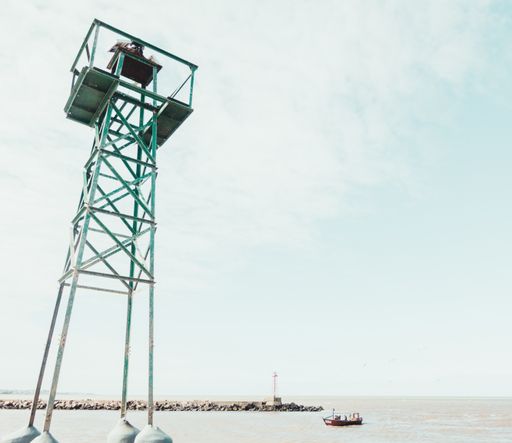 A low angle shot of rescue tower, pier and a boat in the water
