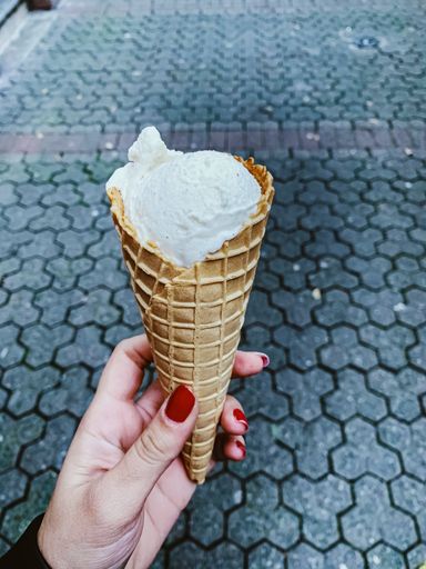 A woman holding a vanilla ice cream cone