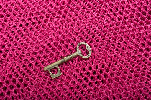 A top view of a retro key with a heart shape on a pink surface- Valentine's concept