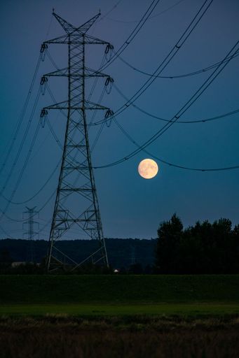 A vertical view of a half moon at night over the valley