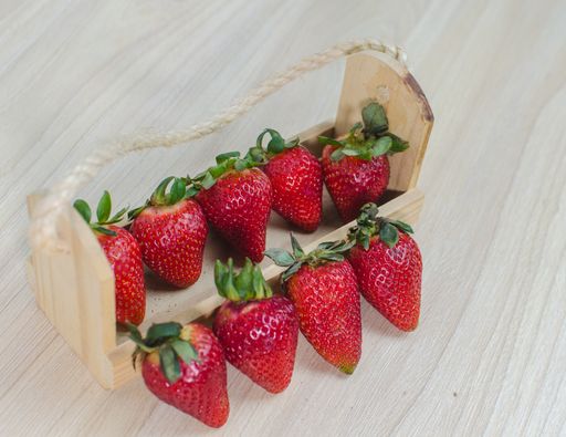 A top view of strawberries in a bowl and some on the table