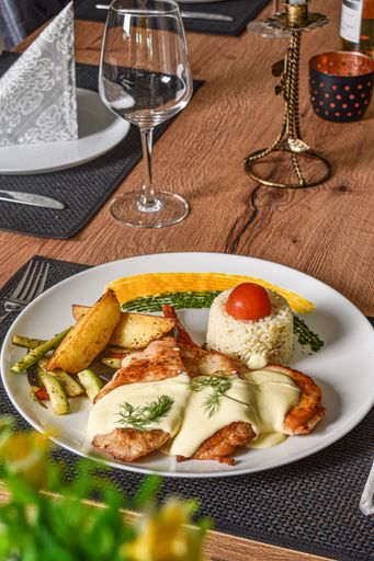 A plate of grilled chicken breast with rice and potatoes on a table