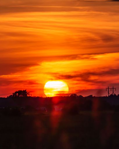 A vertical shot of the golden sunset  in a cloudy sky over the small town