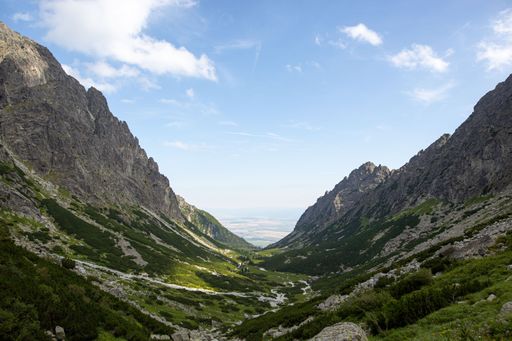 A breathtaking view of a green valley surrounded by rocky cliffs in the High Tatras range in Slovakia