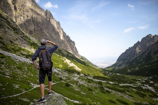 A low-angle shot of little Tarpataki valley with a man's rear view walking, blue sky in the background