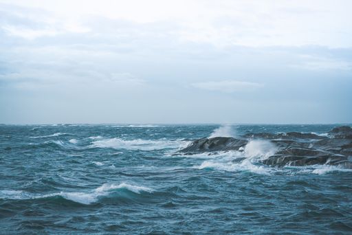 A beautiful shot of waves crashing on rocks under a cloudy sky