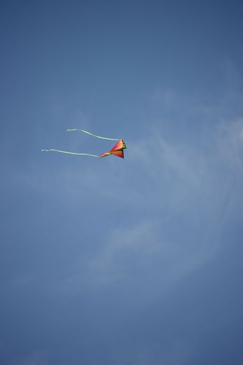A vertical shot of an orange kite in the blue sky. North Carolina.